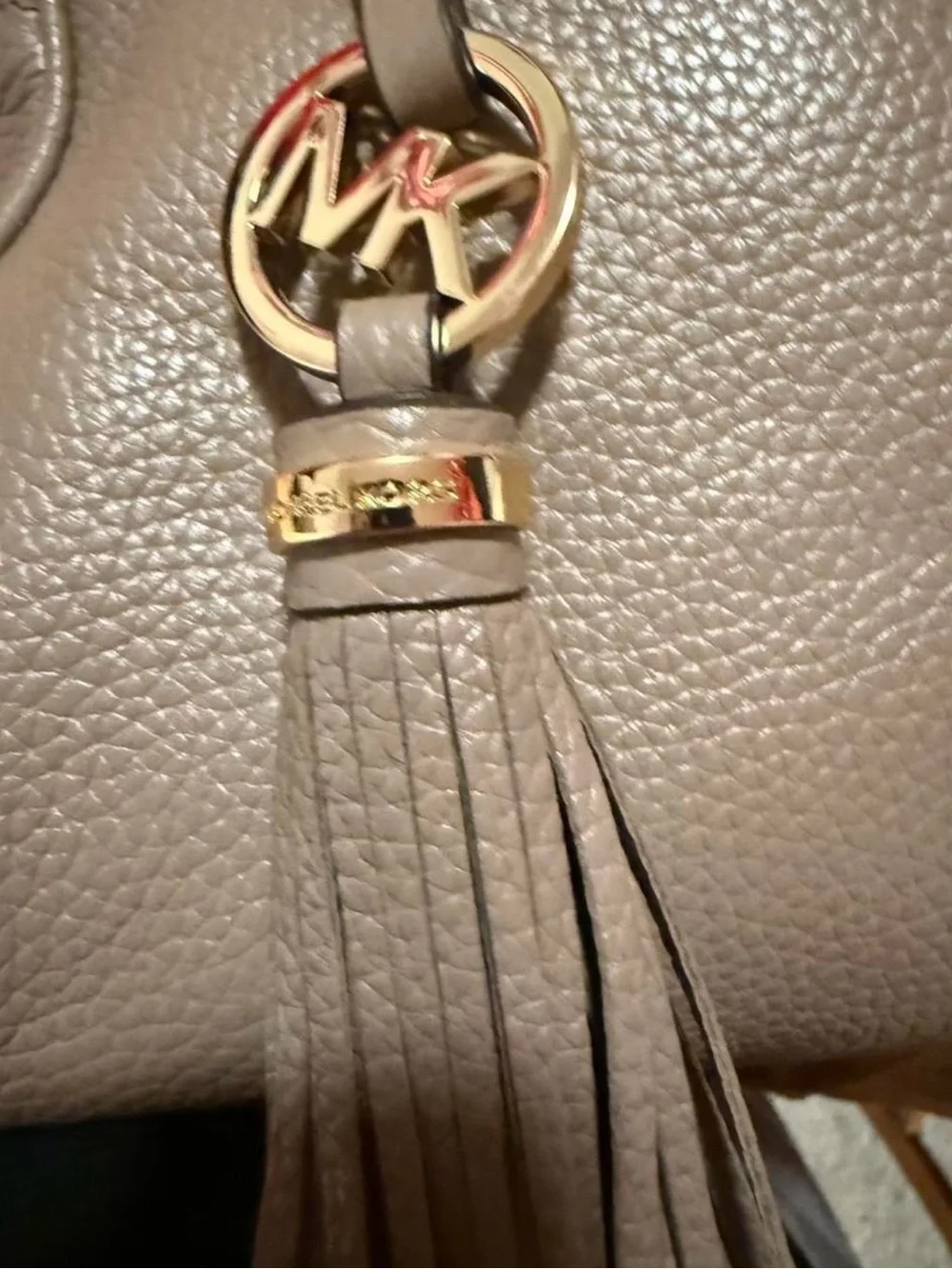 Michael Kors Knox Satchel featuring a prominent tassel and gold-tone hardware